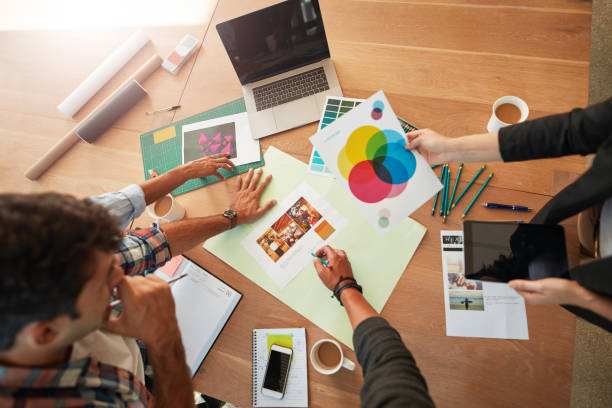 Top view shot of young designers discussing the color palette. Creative team brainstorming around table working together on new project.